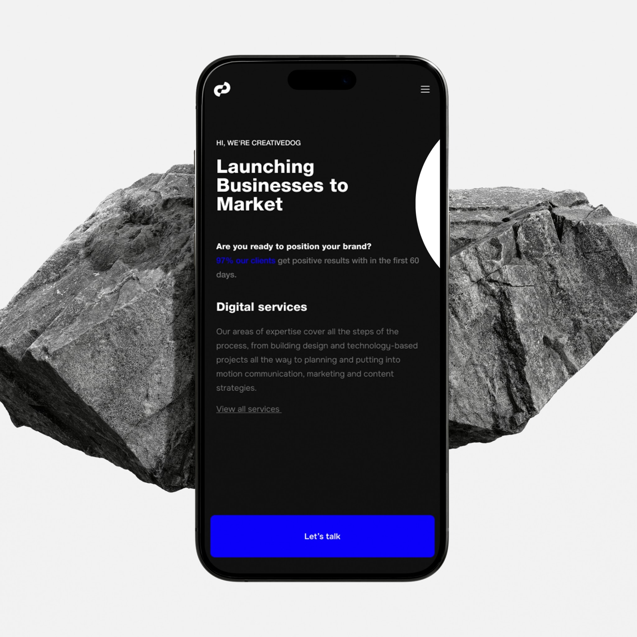 The website's landing page on a phone, over a rock