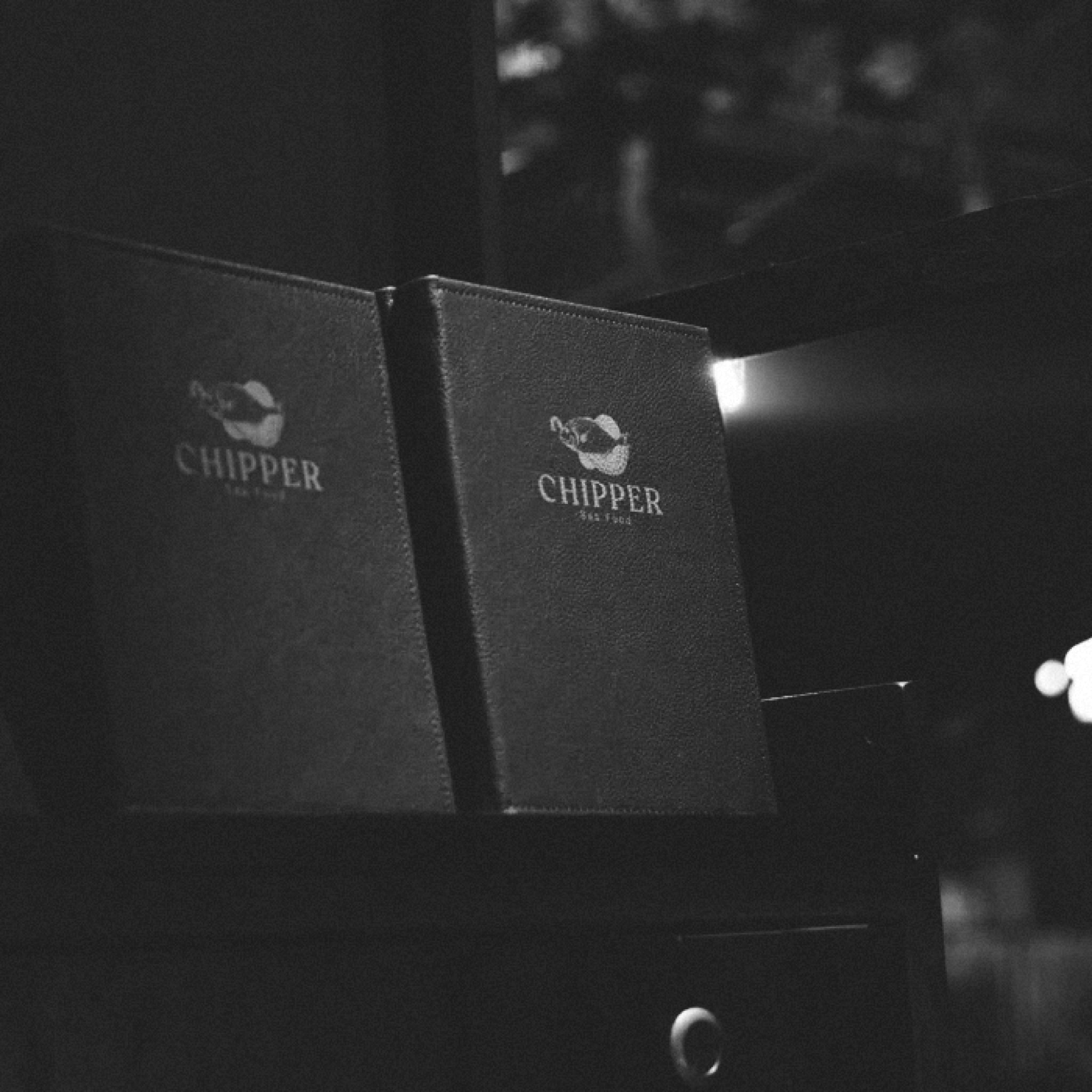 Two black menus with the Chipper mark, in low light