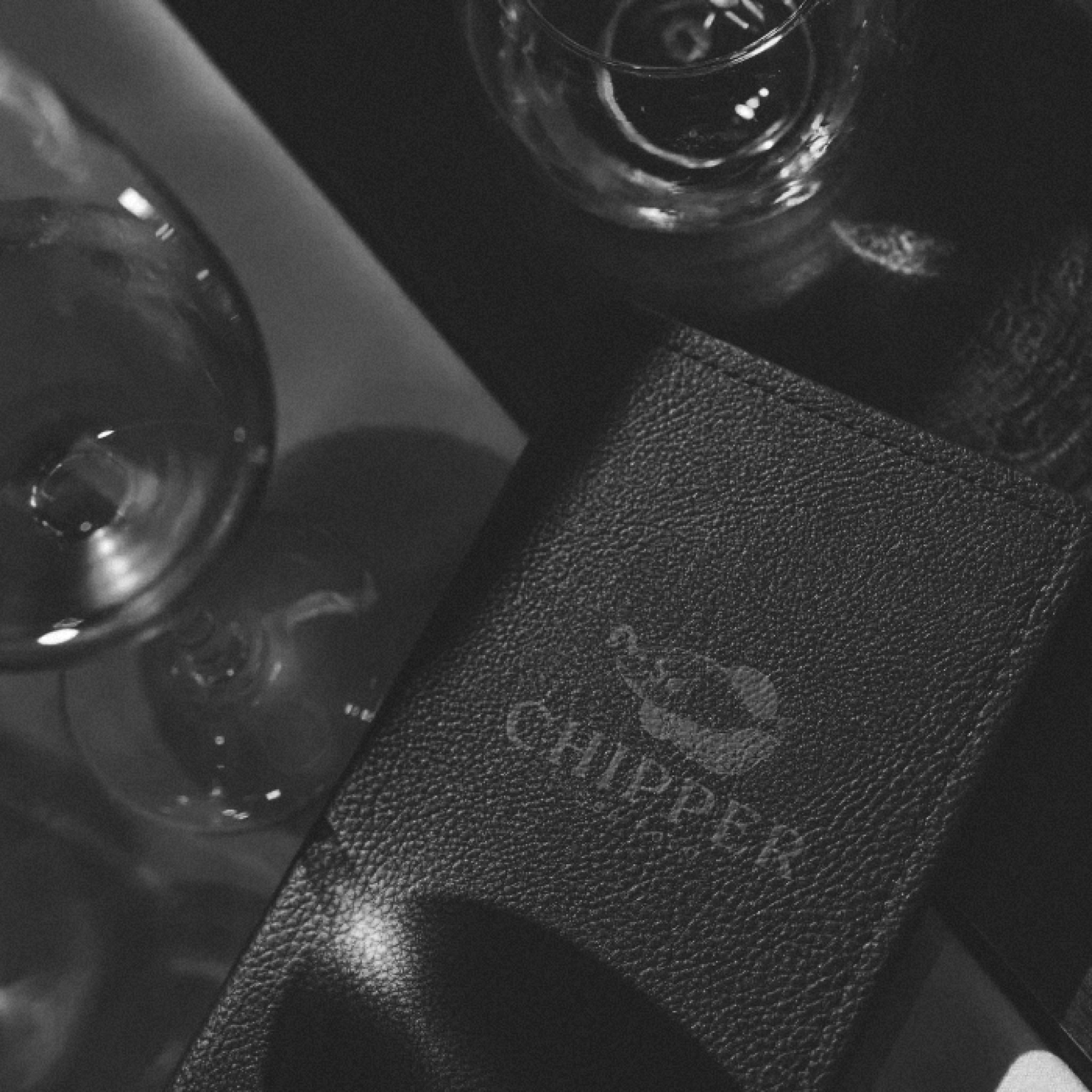 A black leather cover embossed with the mark, beside a wine glass