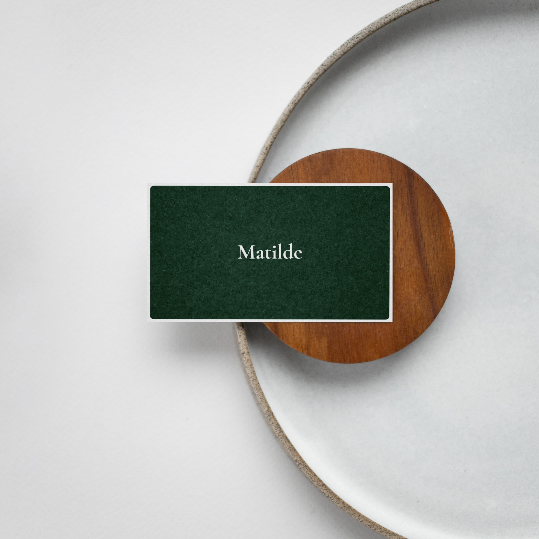The dark green business card on a wooden coaster and a stone plate