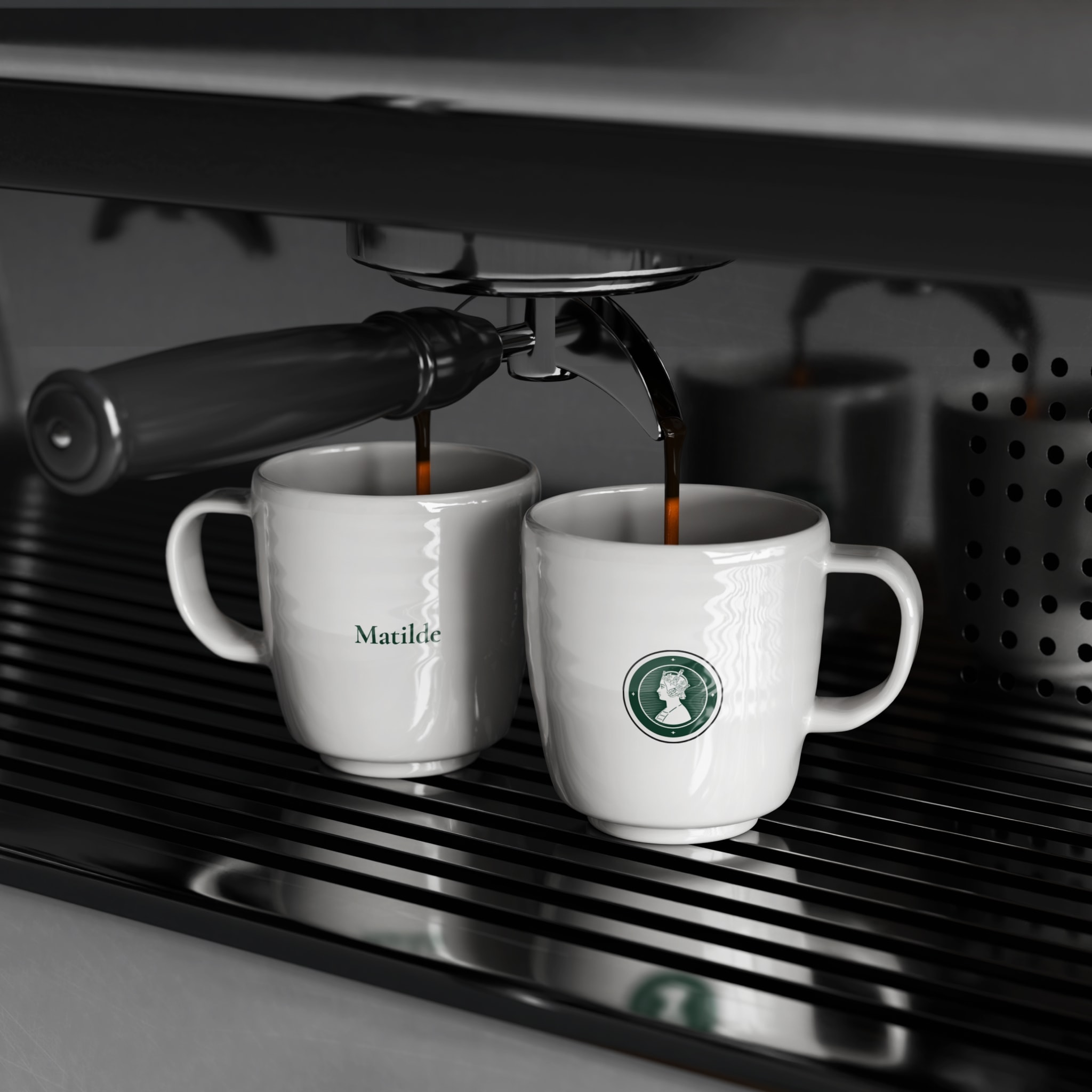 Two espresso cups with the wordmark and the portrait seal, under a coffee machine