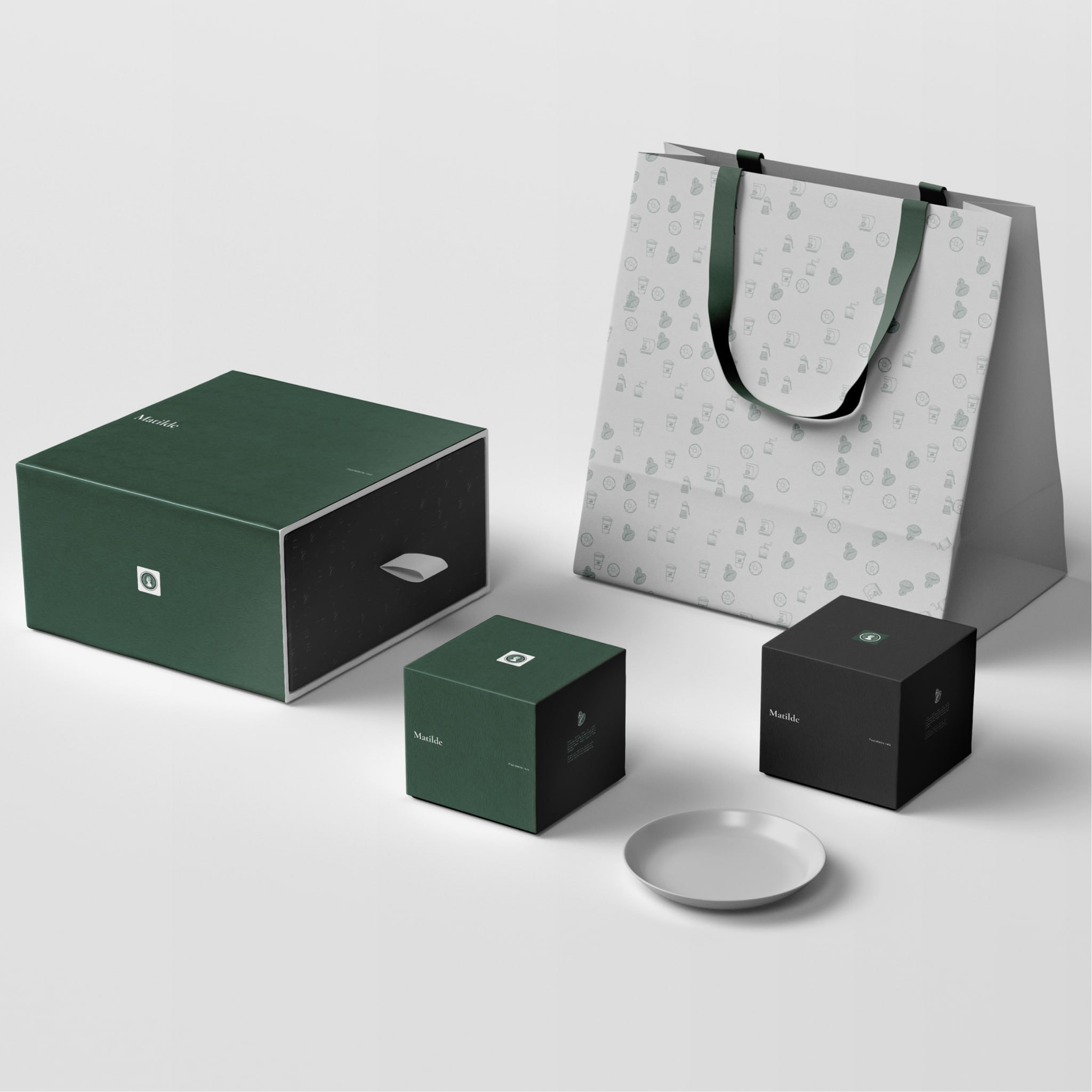 The packaging: green and black boxes, a patterned paper bag and a small dish