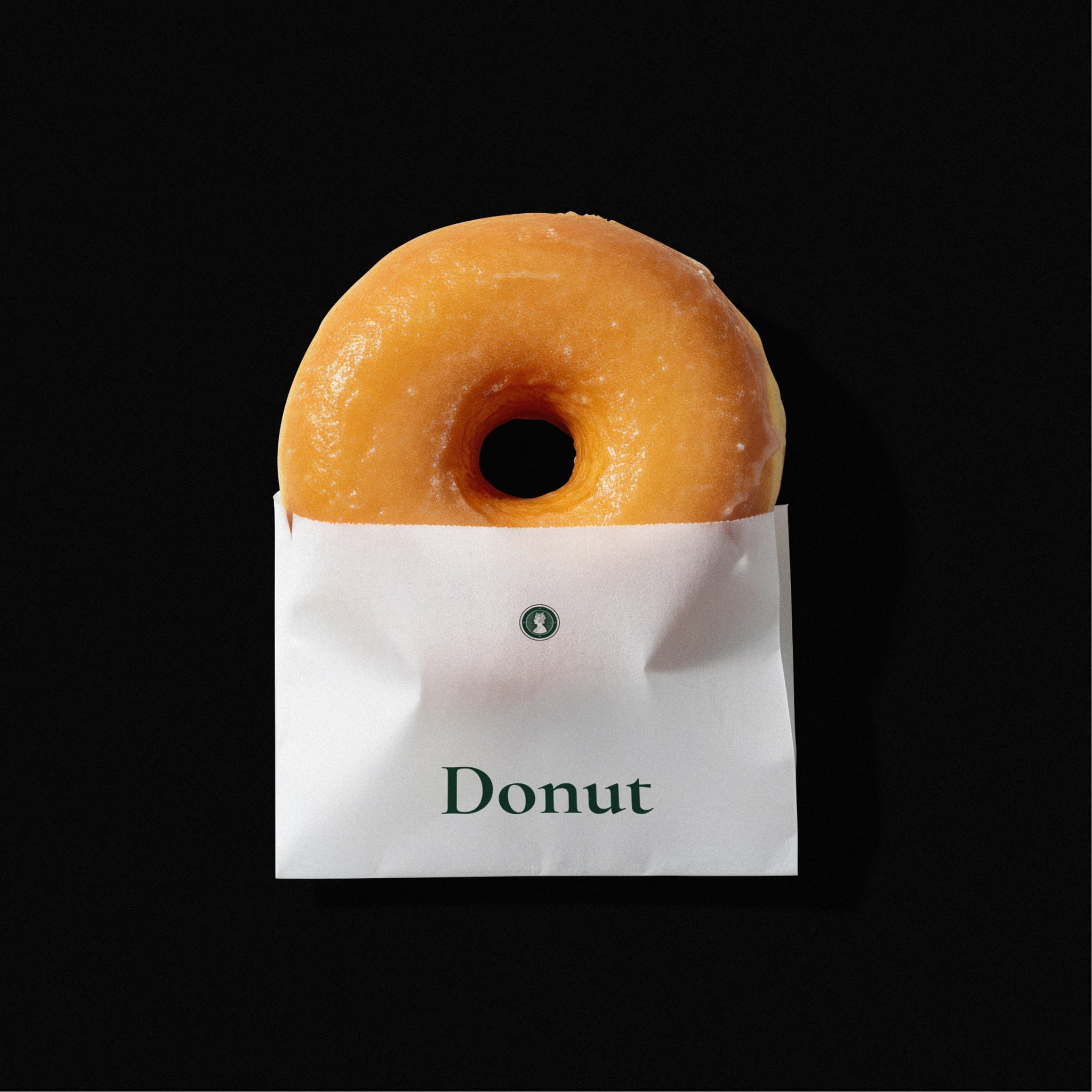 A glazed doughnut in a white paper sleeve that reads Donut