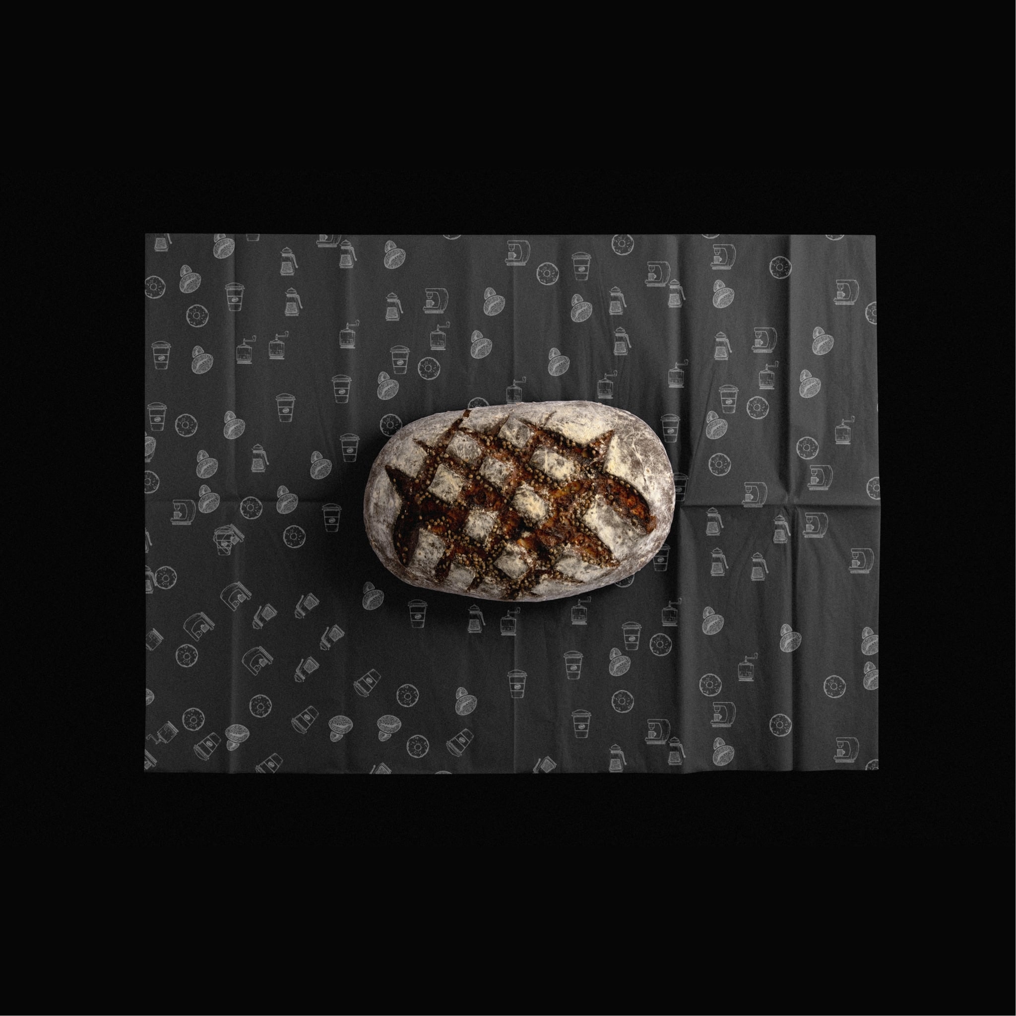 A scored sourdough loaf on black paper printed with the Matilde pattern